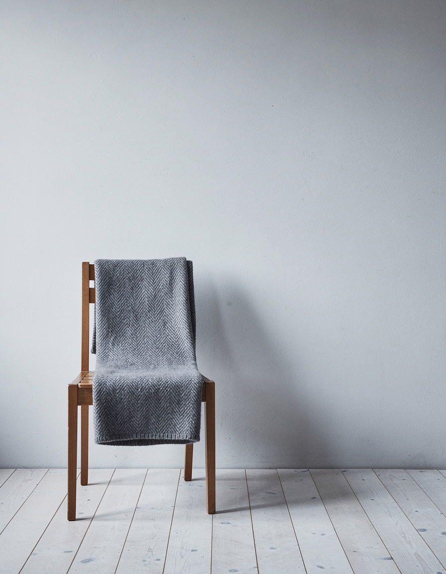 Undyed alpaca throw folded over a plain wooden chair